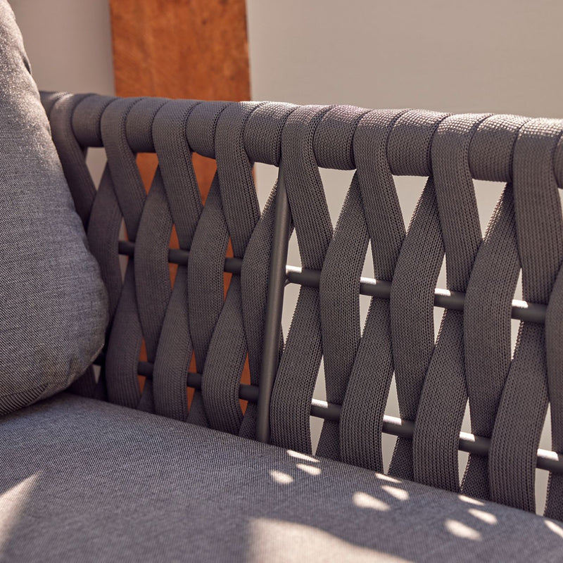 Outdoor furniture set from Lawson Collection featuring a charcoal wicker lounge chair, rope chair, and other pieces. Close-up view of the intricate weave on the rope armchair with matching cushions.