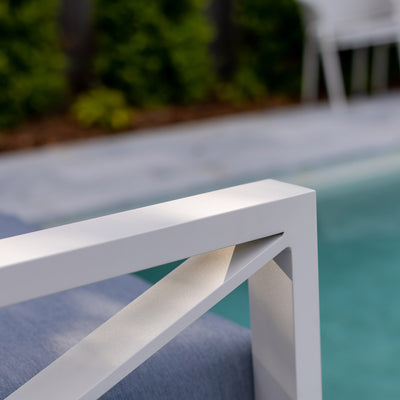 Aluminium outdoor furniture from Linear Lounge collection, including armchair, two-seater, and three-seater outdoor lounge with white frame and light grey cushions beside a pool.