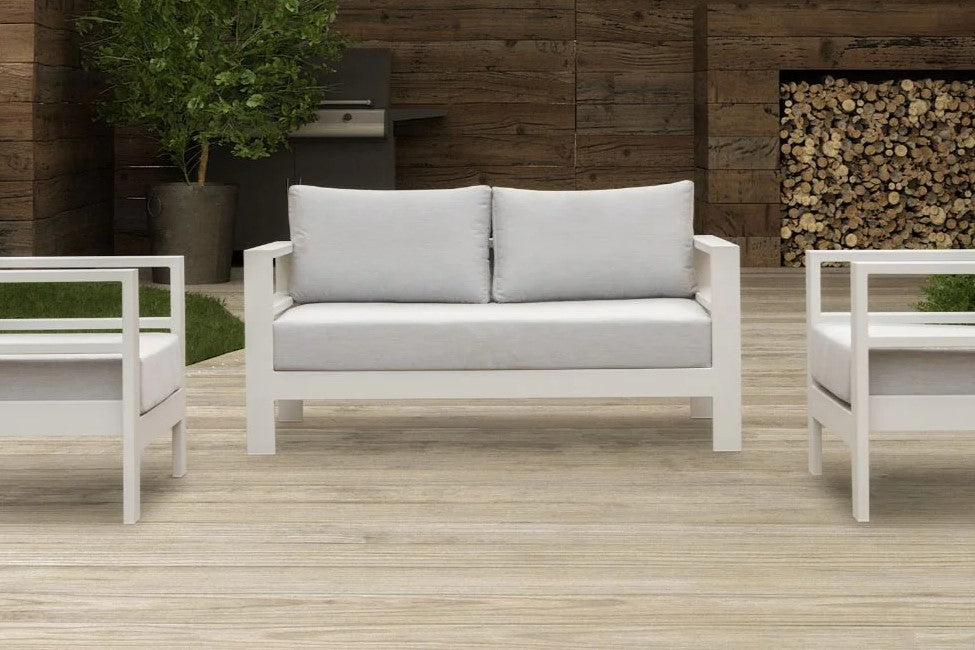 A bright outdoor patio featuring a sleek white 4 seater outdoor lounge set, inviting relaxation and gatherings.