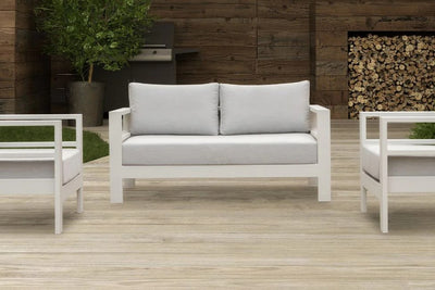 A bright outdoor patio featuring a sleek white 4 seater outdoor lounge set, inviting relaxation and gatherings.