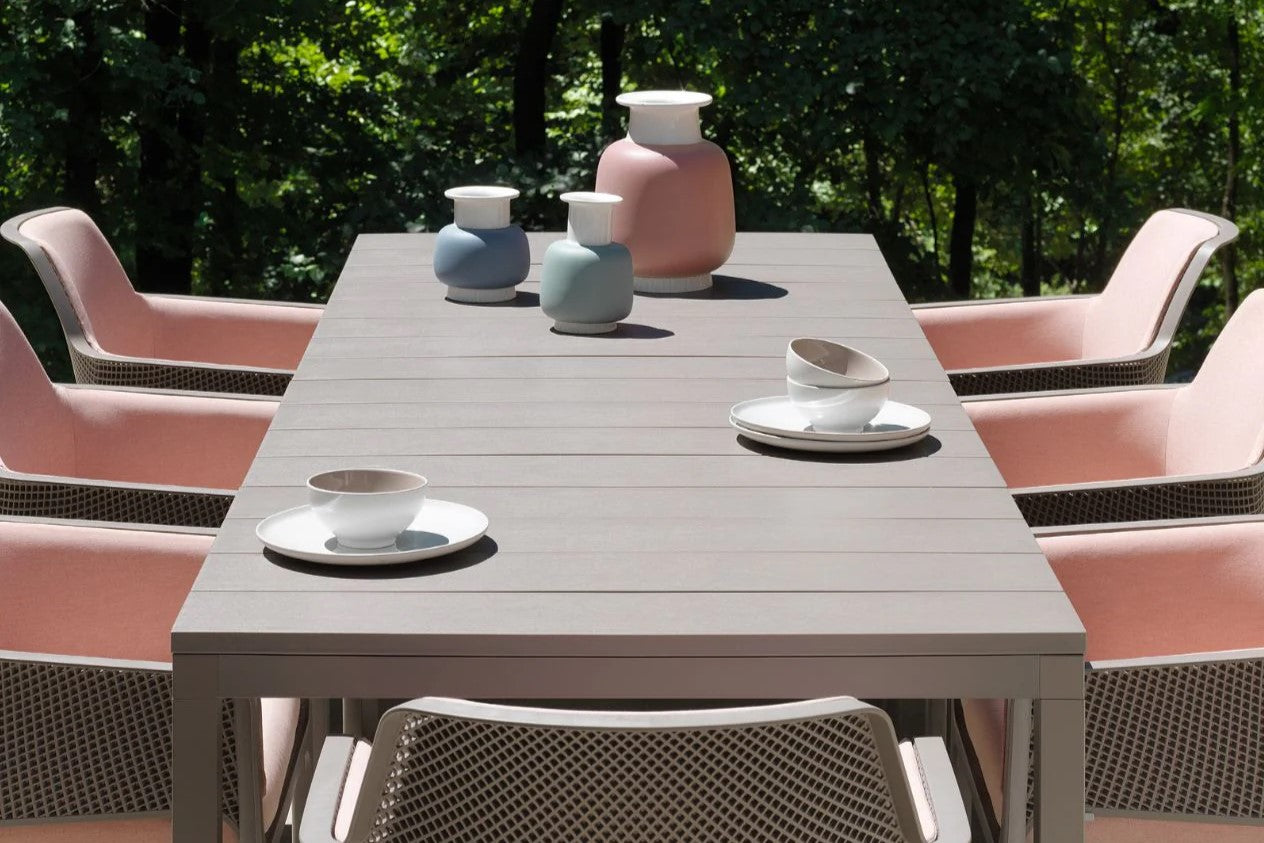 A plastic outdoor table adorned with pink chairs and decorative vases placed centrally on its surface.