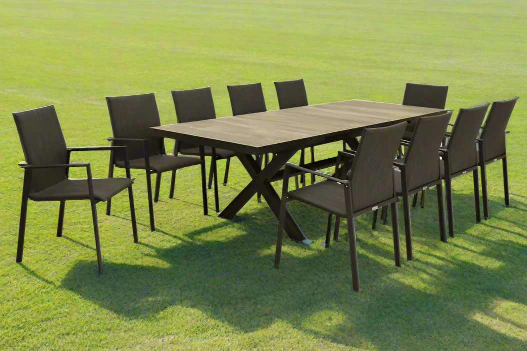 A ceramic outdoor table surrounded by ten aluminium outdoor chairs, making a complete ceramic outdoor dining set, all set on a sunny field of grass.