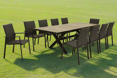 A ceramic outdoor table surrounded by ten aluminium outdoor chairs, making a complete ceramic outdoor dining set, all set on a sunny field of grass.