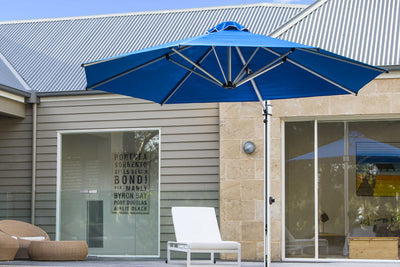 Sleek blue cantilever umbrella in a backyard by the poolside, offering excellent shade for families.
