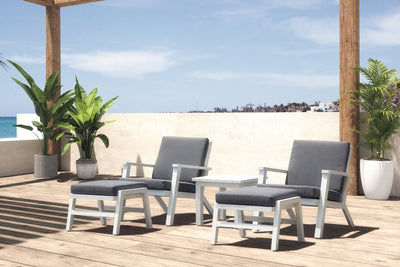 Balcony furniture with two sun loungers and a small coffee table in sunlight, set against a European backdrop with pot plants, creating a beachy vibe.