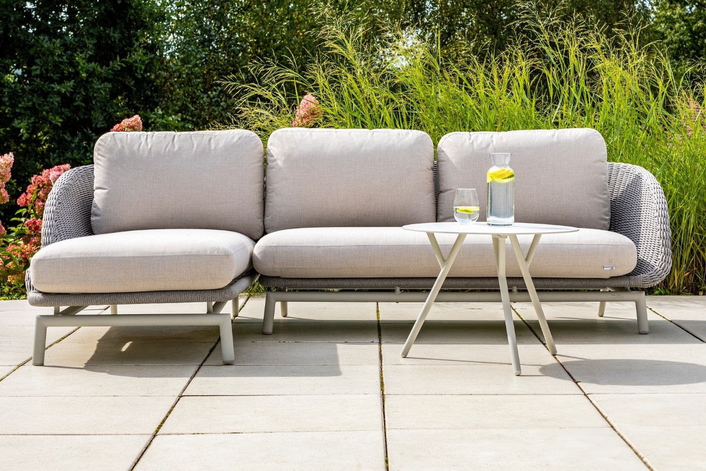 A grey sectional rope outdoor lounge with cushions on a sunlit patio.