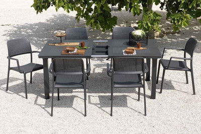 A 6 seater outdoor table with 6 chairs positioned in a shaded area, ideal for enjoying meals or conversations outdoors.