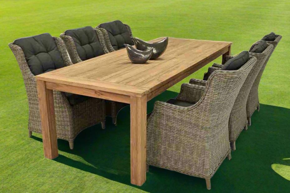A wooden outdoor table surrounded by six outdoor wicker chairs, making a complete outdoor wicker dining set, all set on a big grassy field.