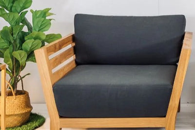 A modern living room featuring an outdoor timber armchair & matching outdoor coffee table, surrounded by greenery.