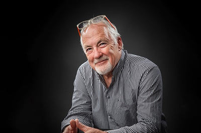 Normand Couture, the designer & founder of the Couture Jardin outdoor furniture brand, sits & smiles comfortably while wearing glasses, radiating warmth and friendliness.