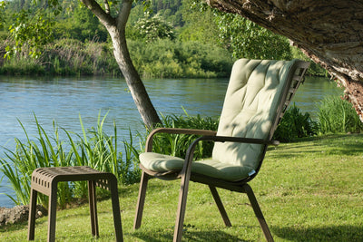 A relaxing green outdoor chair and footstool. This set comes from Nardi’s amazing range of balcony chairs and is placed beside a river and surrounded by lush greenery.