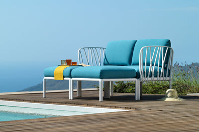 Vibrant blue Nardi lounge set on an outdoor wooden deck beside a pool, with a stunning view of mountains, greenery, and blue skies.