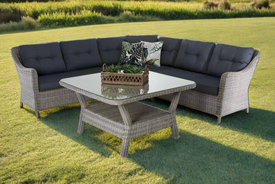 Outdoor furniture set featuring a wicker outdoor modular lounge and wicker coffee table set in a big sunny field.