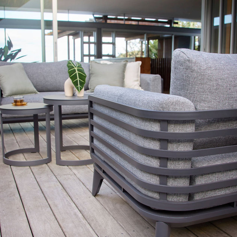 Alora range outdoor furniture including a 1-seater and 5-seater outdoor lounge on a wooden deck, made of airy aluminium and durable cushions, built to withstand the Aussie sun.