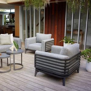 Alora range aluminum outdoor furniture set on a patio, including a 1-seater and 5-seater outdoor lounge chairs, surrounded by plants.