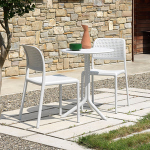 Two white resin chairs paired with a white round table, forming a stylish alfresco furniture set, positioned outdoors in the sun.