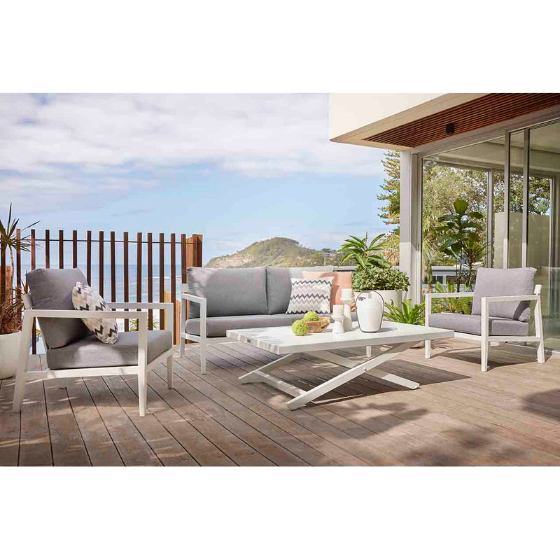 Bradford aluminum outdoor furniture set on a patio, featuring a sleek outdoor lounge chair, couch, table and chairs in charcoal and white.