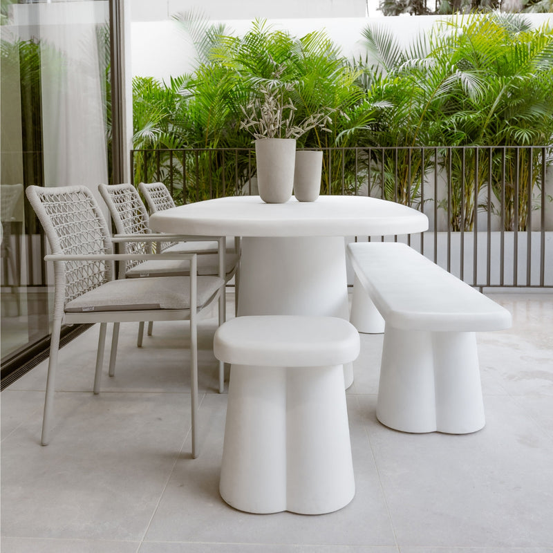 Contemporary concrete outdoor dining set in white and grey, set against a backdrop of greenery, creating a sophisticated alfresco furniture atmosphere.