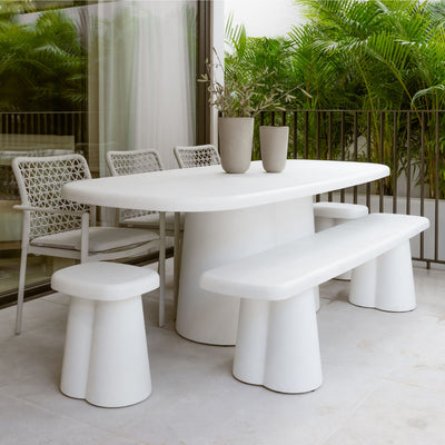 Modern concrete outdoor dining set in white and grey tones, surrounded by greenery in the outdoor area, offering a sleek and stylish alfresco furniture setting.