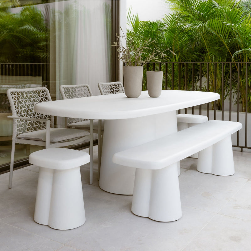Modern concrete outdoor dining set in white and grey tones, surrounded by greenery in the outdoor area, offering a sleek and stylish alfresco furniture setting.