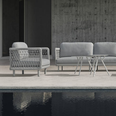 The image displays a modern outdoor armchair featuring a light grey rope design for the armrests and backrest. The seat cushion is a matching light grey, and the chair is set against a neutral outdoor background with stone tiles.