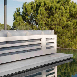 Charcoal and white Como sofa, a versatile piece of aluminum outdoor furniture, ideal as outdoor balcony furniture, sitting by a pool in a forest.