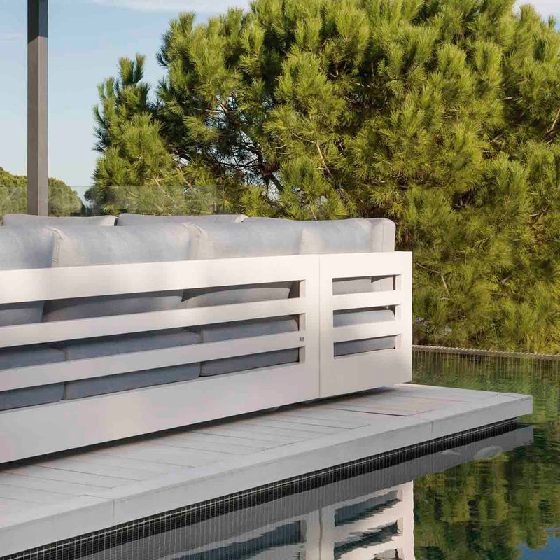 Charcoal and white Como sofa, a versatile outdoor balcony furniture piece, part of aluminum outdoor furniture collection, placed by a pool in a forest setting.