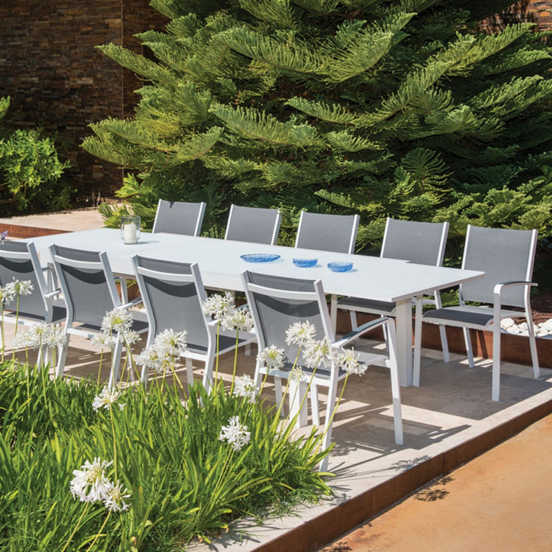 Aluminium outdoor dining furniture, Cosmo outdoor chairs in charcoal and white, with teak and ceramic tables in a garden.