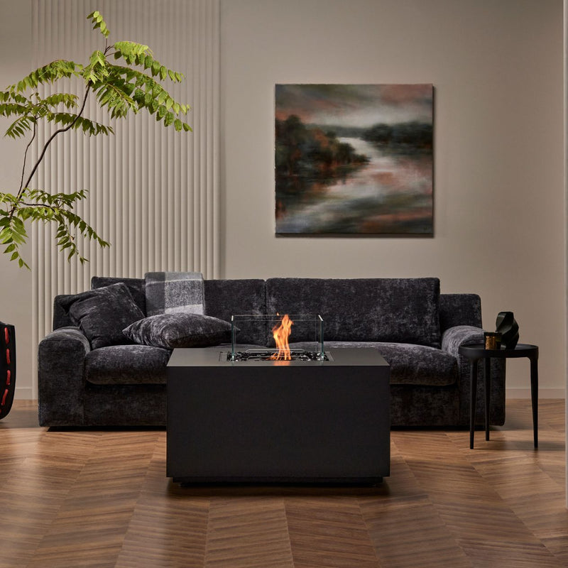 Black square firepit set in a lounge area amongst furniture, creating a cozy and stylish gathering spot.
