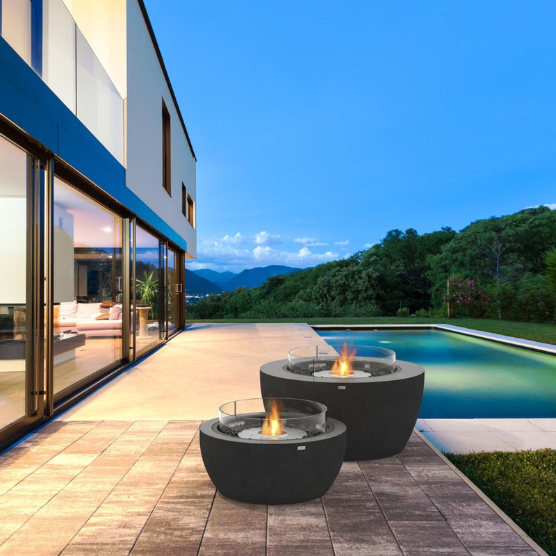 Two cylindrical black EcoSmart Pod 40 firepits set poolside in an outdoor area, enhancing the poolside outdoor furniture setting.
