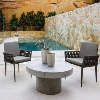 Two dark grey Lawson outdoor rope dining chairs paired with a round concrete table, set poolside, offering a chic alfresco furniture dining experience.