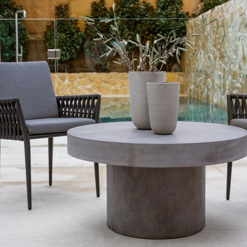 Two dark grey Lawson outdoor rope dining chairs paired with a grey round concrete table with two pot plants, set poolside, exemplifying modern alfresco furniture design.