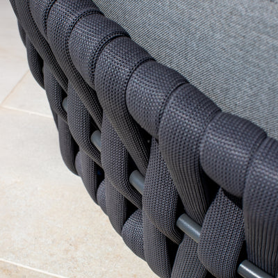 Close-up of a woven rope detail on a daybed, showcasing intricate charcoal weaving against a neutral outdoor surface, emphasizing modern outdoor furniture design.