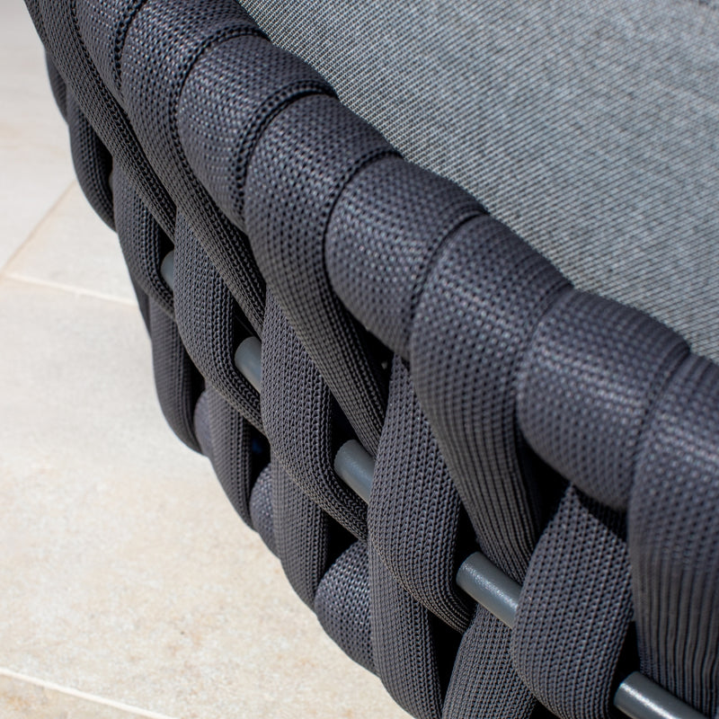 Close-up of a woven rope detail on a daybed, showcasing intricate charcoal weaving against a neutral outdoor surface, emphasizing modern outdoor furniture design.