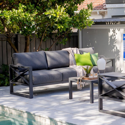 Aluminium 3 seater outdoor lounge with charcoal frame and cushions, accompanied by an outdoor lounge chair, part of the robust aluminium outdoor furniture collection by the pool.