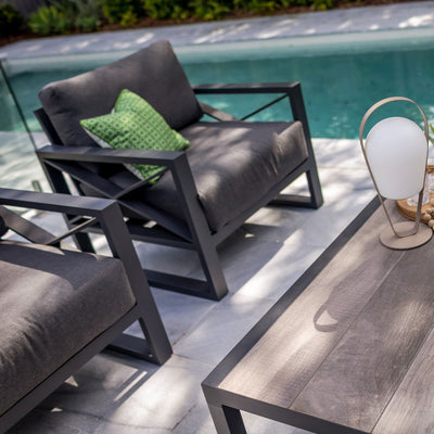 Aluminum outdoor furniture from Linear Lounge collection, including outdoor chairs and lounge, near a pool