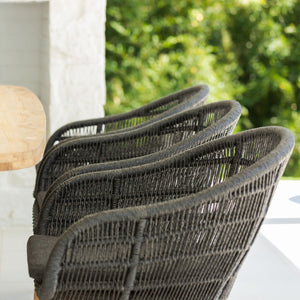 Outdoor furniture: A wicker dining chair with black frame and charcoal fabric set outdoors with trees in the background.