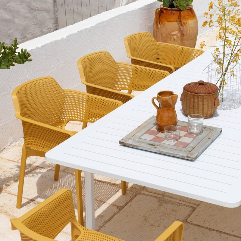 White 210/280 cm Nardi Alloro Resin Extension Dining Table with eight matching bright yellow chairs, set on a stone outdoor area, ideal for alfresco furniture setups, with some cutlery placed on the table.