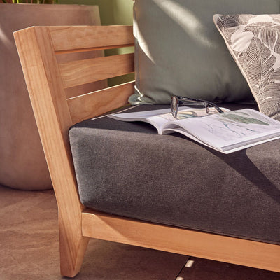 Outdoor balcony furniture from The Ottawa family, featuring outdoor chairs, a 3-seater outdoor lounge, and a daybed, all made of durable teak wood and Sunproof® fabric. Current image: A wooden chair with a book and glasses on it.