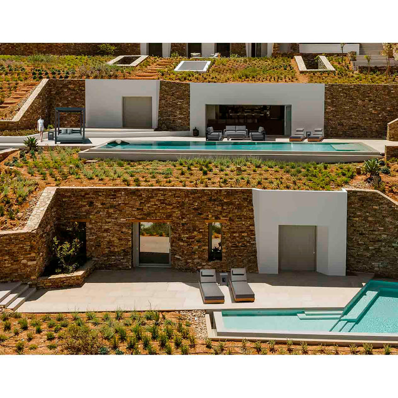 A modern, multi-level outdoor area of a large house. On the bottom level, two brown and grey aluminium &