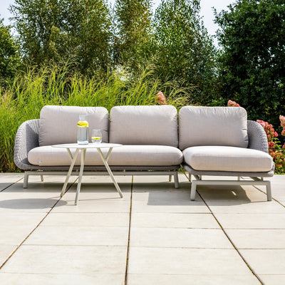 Outdoor setting featuring the Sorrento Daybed by Couture Jardin, crafted with woven Olaphen rope and complemented by plush light-colored cushions.Surrounded by vibrant hydrangeas and lush greenery, creating a serene and stylish lounging space.