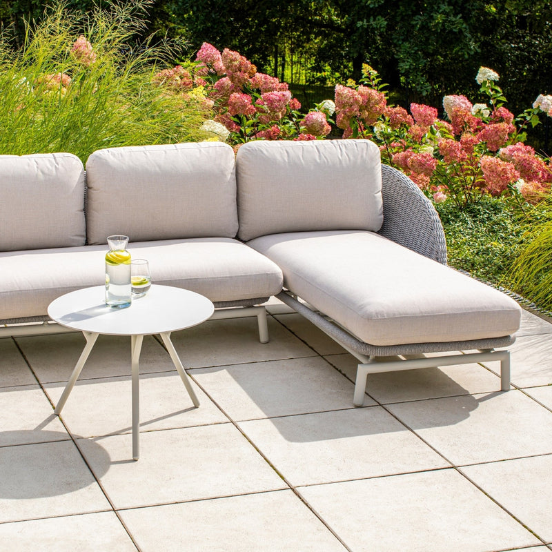 Outdoor setting featuring the Sorrento Daybed by Couture Jardin, crafted with woven Olaphen rope and complemented by plush light-colored cushions.Surrounded by vibrant hydrangeas and lush greenery, creating a serene and stylish lounging space.