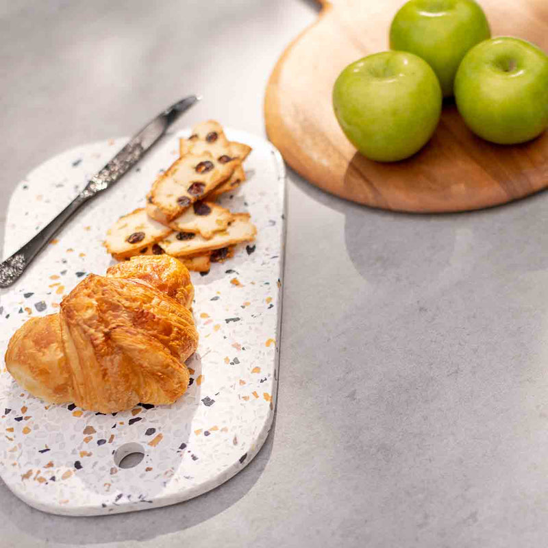 Close-up of the Trivento table top featuring fruit, bread, and cutlery, showcasing the Spanish Neolith® ceramic surface in an outdoor area.