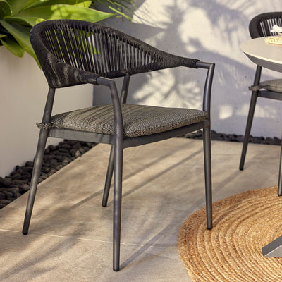 Outdoor furniture: The Windsor Dining Chair, a rope chair with charcoal frame and fabric, set outdoors with plants.