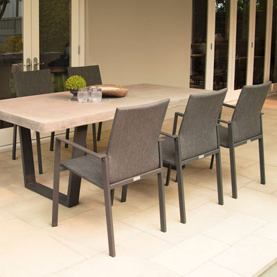 Concrete & aluminium dining set in an outdoor area. The table is set with drinks & a plant, perfect for alfresco furniture setups.