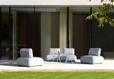 Aluminium outdoor furniture set on a patio, featuring an elegant Iowa coffee table in light grey, couch, chair, and outdoor dining furniture.