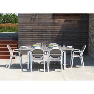 Brown and white alfresco furniture dining set featuring an extendable table and matching chairs, arranged outdoors in the sun with water glasses and cutlery on the table.
