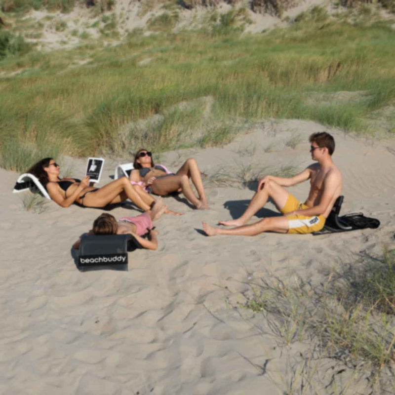 Four people in a circle on the beach: two girls and two guys. The girls are using white &