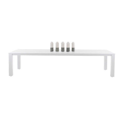 A modern rectangular aluminium outdoor dining table with a sleek white surface and minimalist design, set against a plain white background. The table has 4 white candles on top of it.