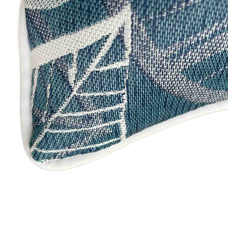 Close-up on the corner of a blue, grey, and white outdoor scatter cushion with a lakeside-inspired leaf pattern design, perfect for outdoor furniture setups.
